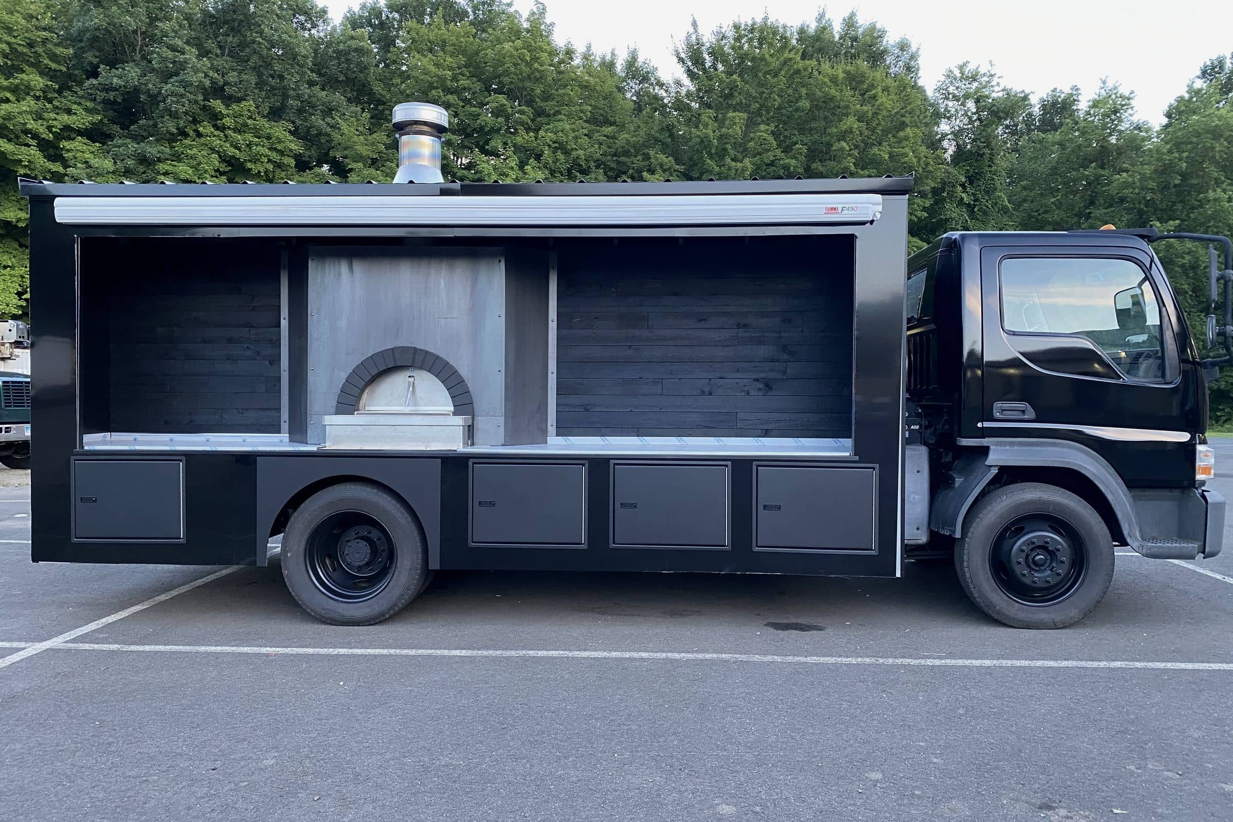 Side profile of The Fire Pizza Company Ford wood-fired pizza truck with Valoriani oven