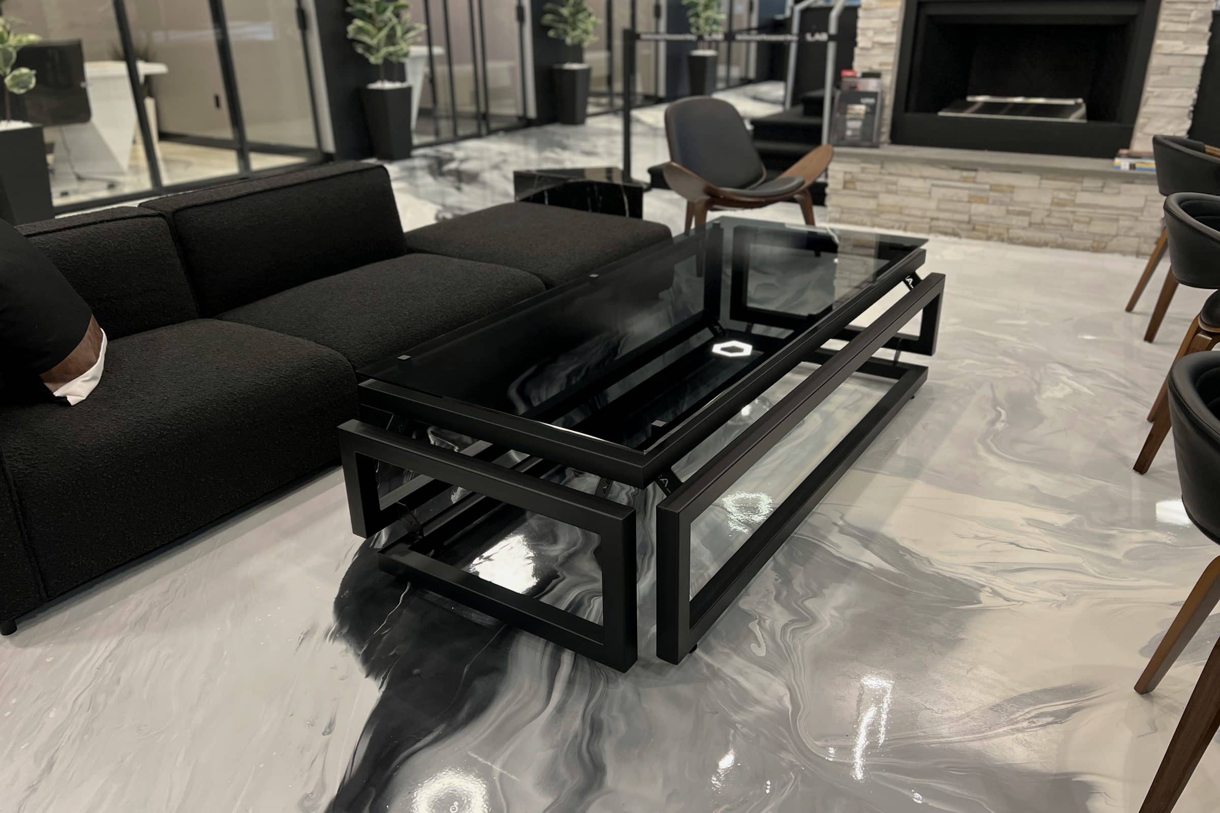 Glass-top infinity table with a black steel frame in a showroom
